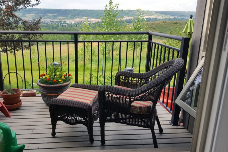 pa small patio with a chair, footrest and potted plants with railing round it