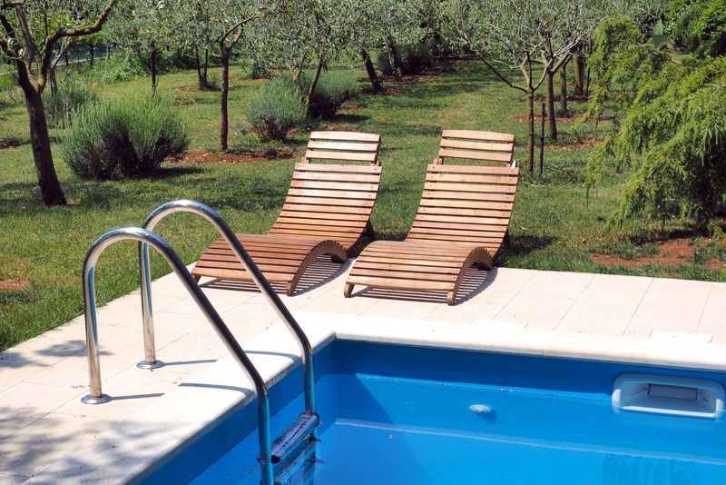 pool deck with two pool lounge chairs and a well trimmed lawn all round