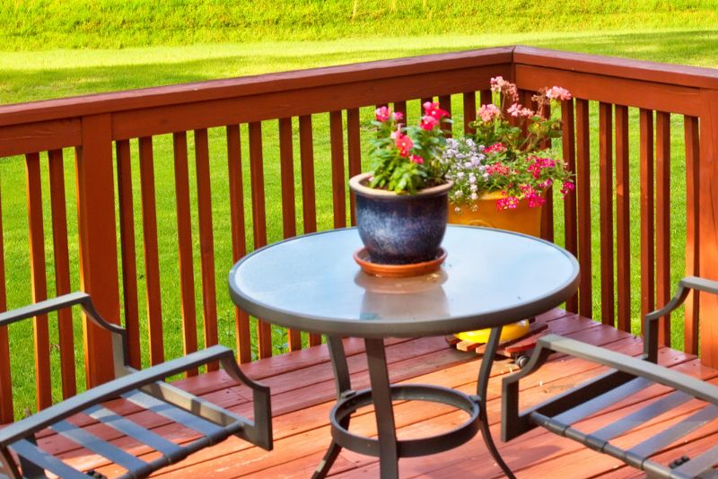 timber deck with a table two chairs and a potted flower