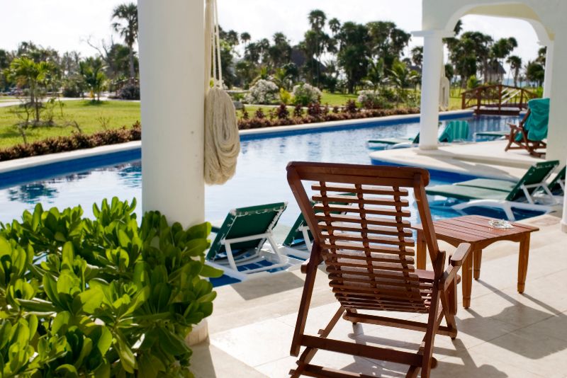 modern pool deck with concrete floors and pool lounge chairs all round and a potted plant